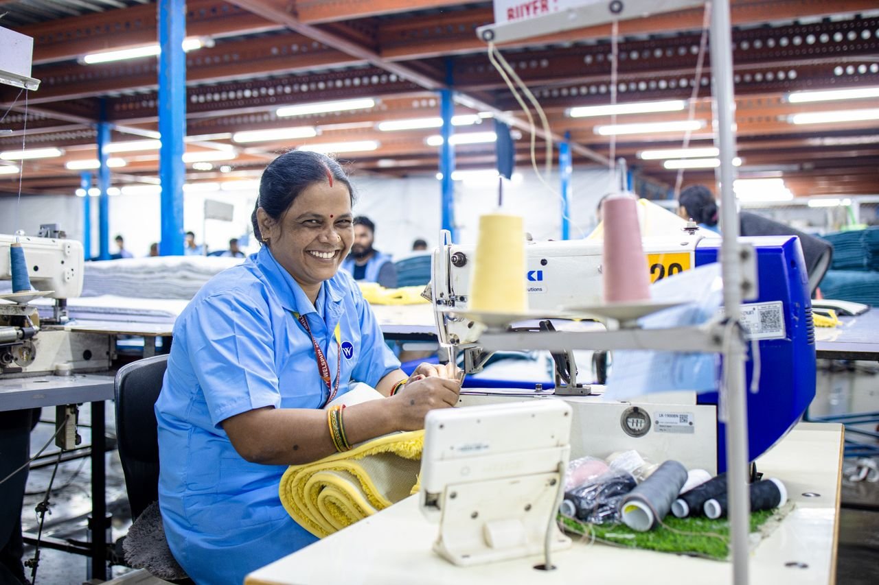 A joyful textile worker busy with sewing in a vibrant factory setting.