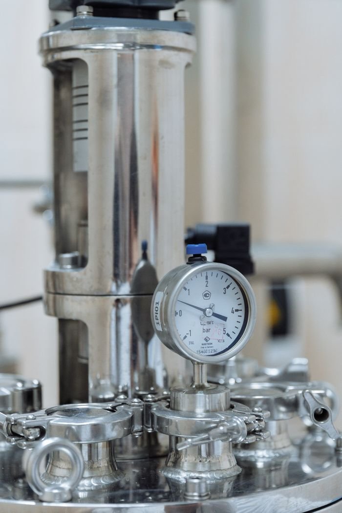 services-02 Detailed view of a stainless steel pressure gauge in a laboratory or industrial setting.